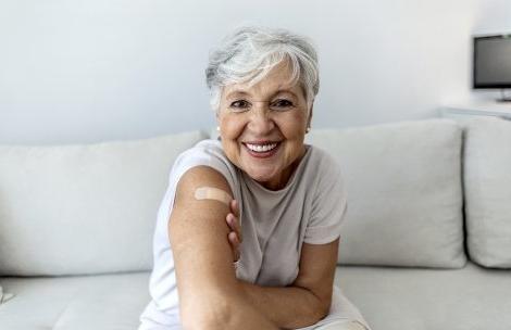 一名老年妇女在接种疫苗后自豪地展示她缠着绷带的手臂.